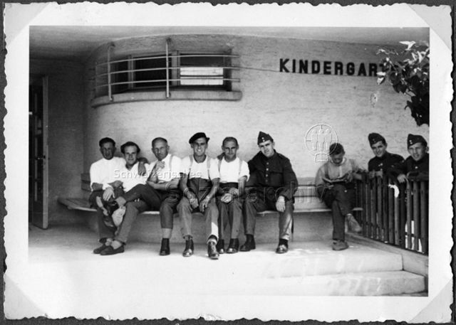 Album Alfred Brauchli, Teil 1/3: 699 Tage Aktivdienst 1939-1945 als Sanitätssoldat bei der Sanitätskompanie I/​7, Thurgau: Alfred Brauchli (2.v.l.) vor einem Gebäude, das mit "Kindergarten" beschriftet ist