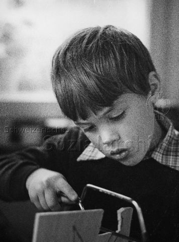 "Freizeitbeschäftigung innen" - Junge bei Laubsägearbeiten; um 1975