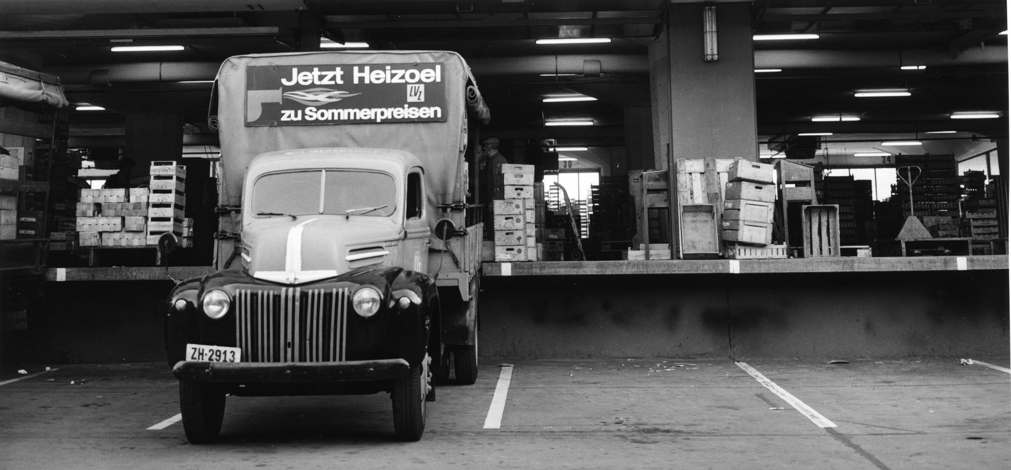 Lieferwagen an der Rampe eines Lagerhauses, Aufschrift: "Jetzt Heizöl zu Sommerpreisen"