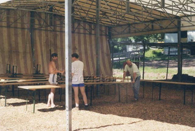 Bosco della Bella, Feriendorf für kinderreiche Familien - Drei Männer beim Auf- oder Abbauen von Festbänken in Festzelt; 2000