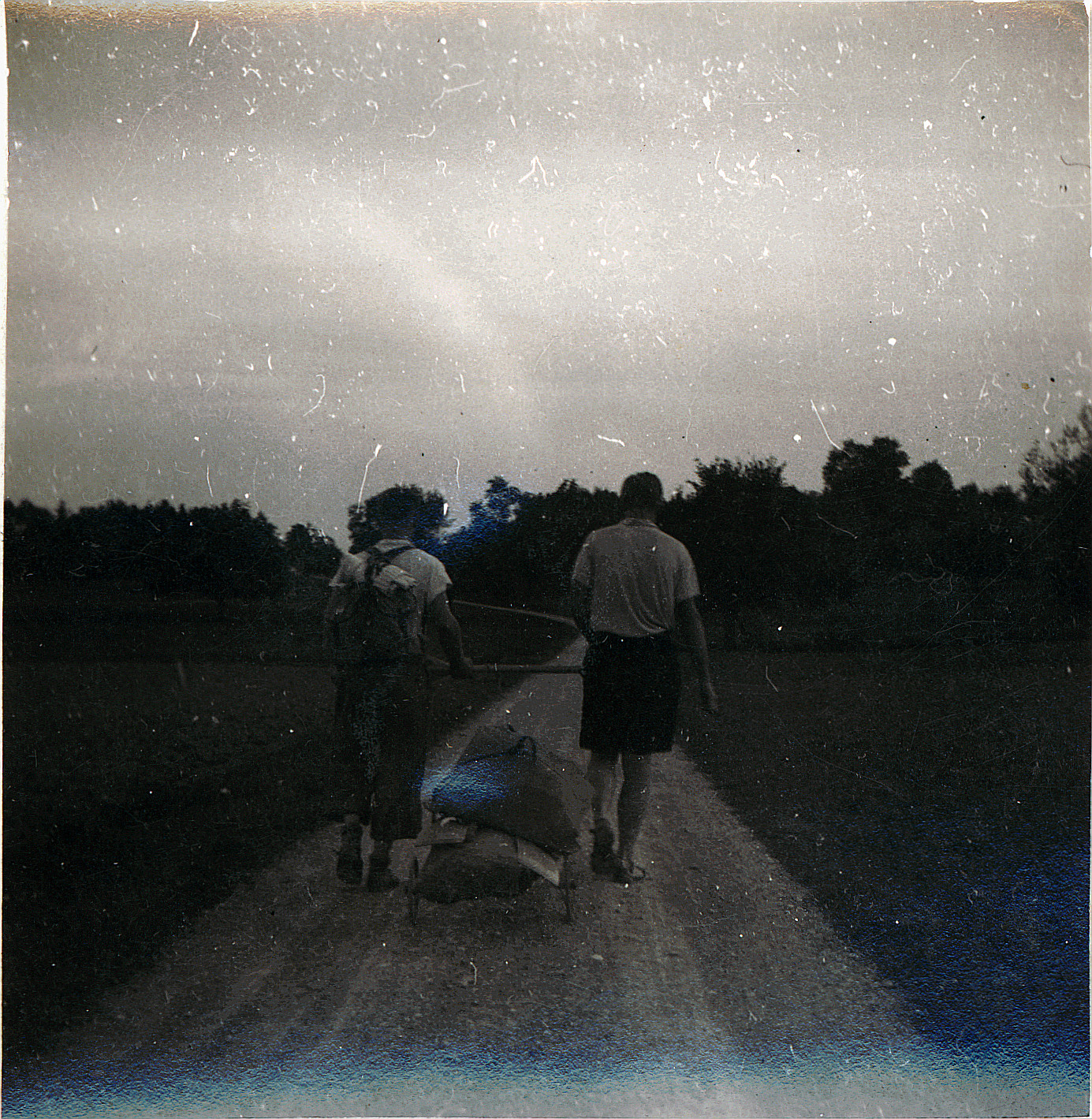 Wandervogeltreffen: EM 2 - Zwei Wandervögel laufen auf einem Schotterweg und ziehen einen Wagen mit Gepäcken (vermutlich 1919)