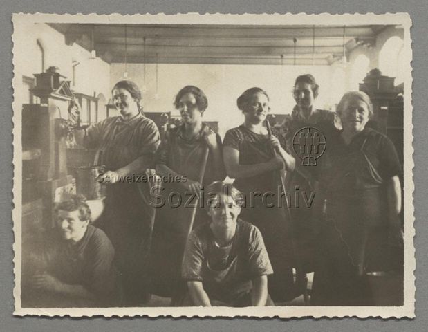 Gruppenbild von Putzfrauen der Universität Zürich in Raum mit Holzinterieur und Waschbecken, vorne Theresia Jäggin (genauere Lokalisation unklar)
