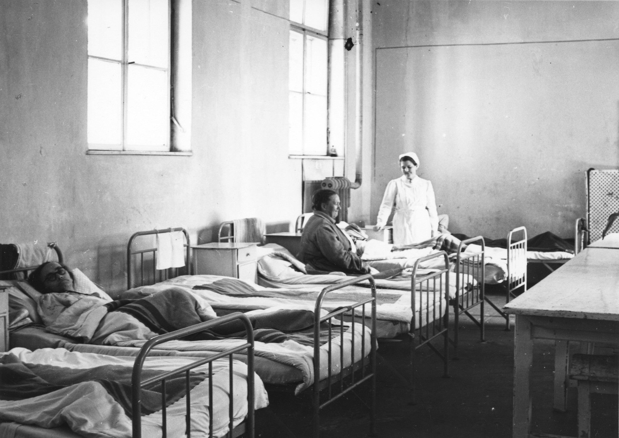 "Rekonvaleszentenheim für Flüchtlinge Wien 12, Okt. 1949", Patienten in ihren Betten und Krankenschwester