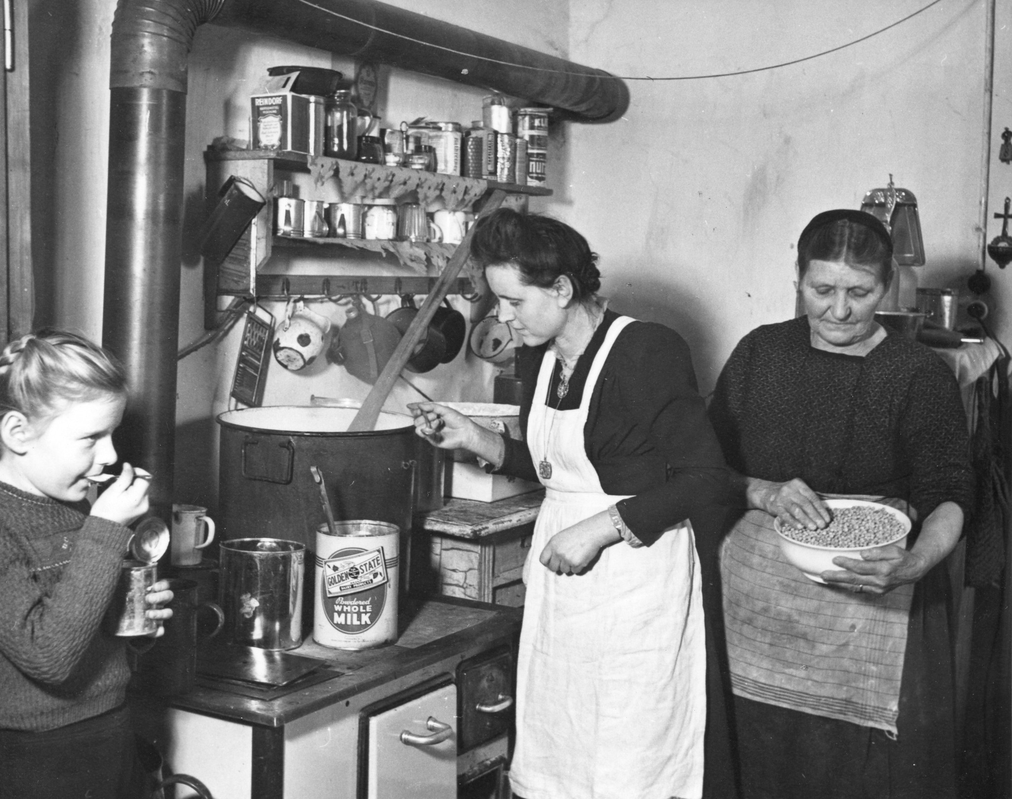 "Städtischer Flüchtlingsheim Arsenal, Wien 10.", Flüchtlinge beim Kochen, ein Mädchen beim Essen, Februar 1949