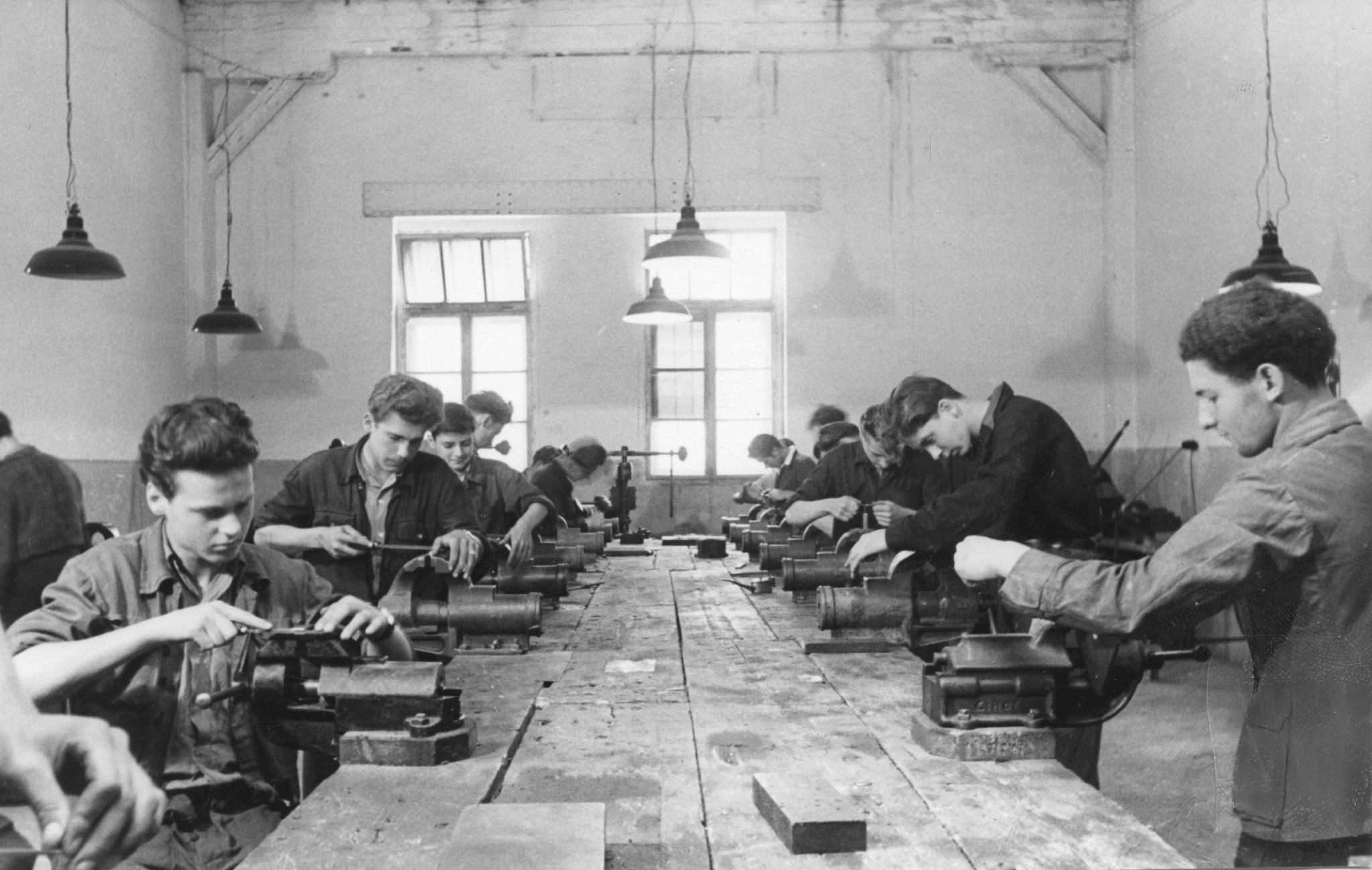 "Österreichische Lehrwerkstätten. Kaum war die Mittagszeit vorüber, begann die Arbeit in der Werkstätte", Auszubildende beim Feilen, Wien, um 1950