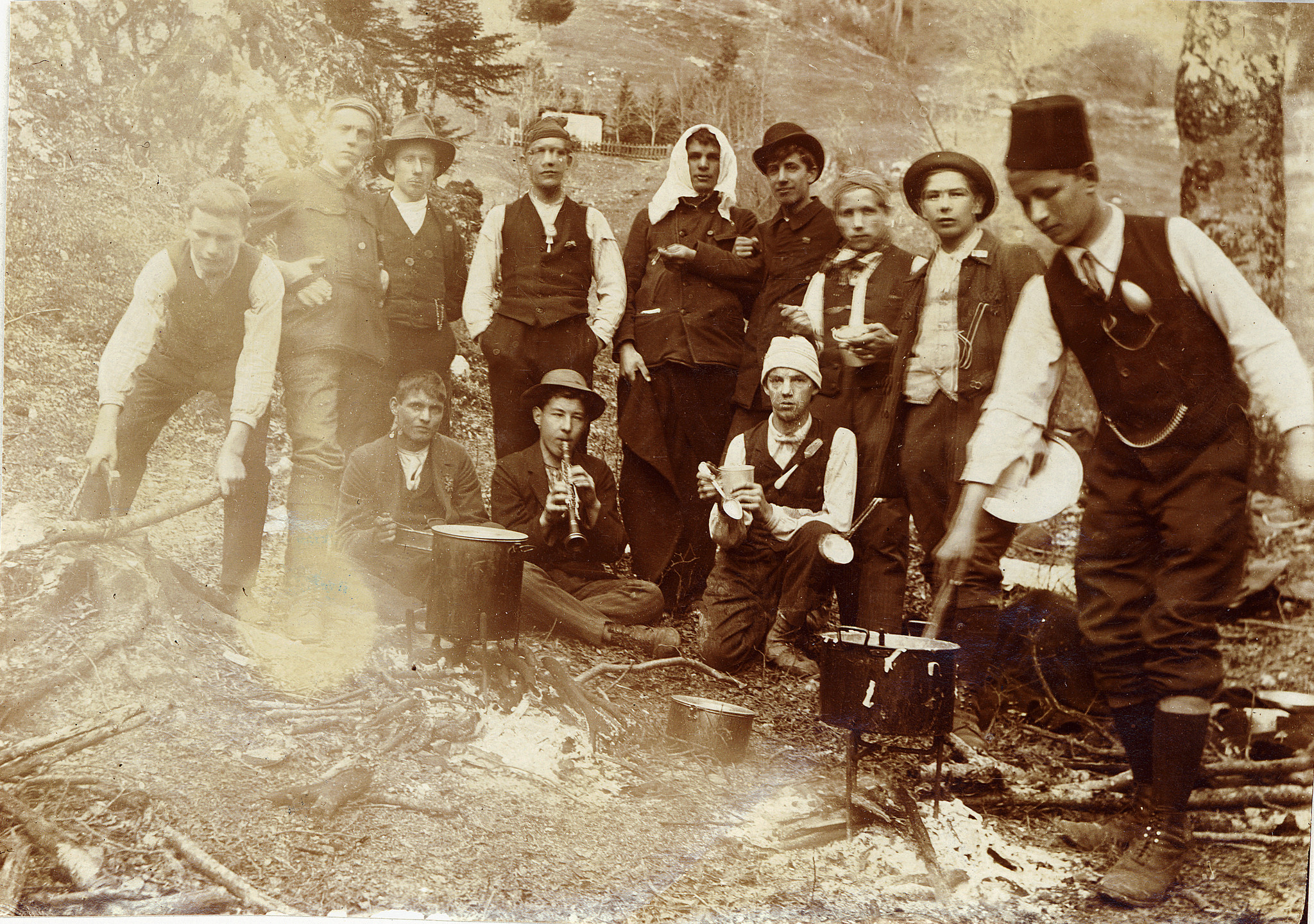 Wandervögel am Westschweizerischen Wandervogeltag in Magglingen kochen auf dem Feuer - Ein Wandervogel Klarinette spielend (1912)