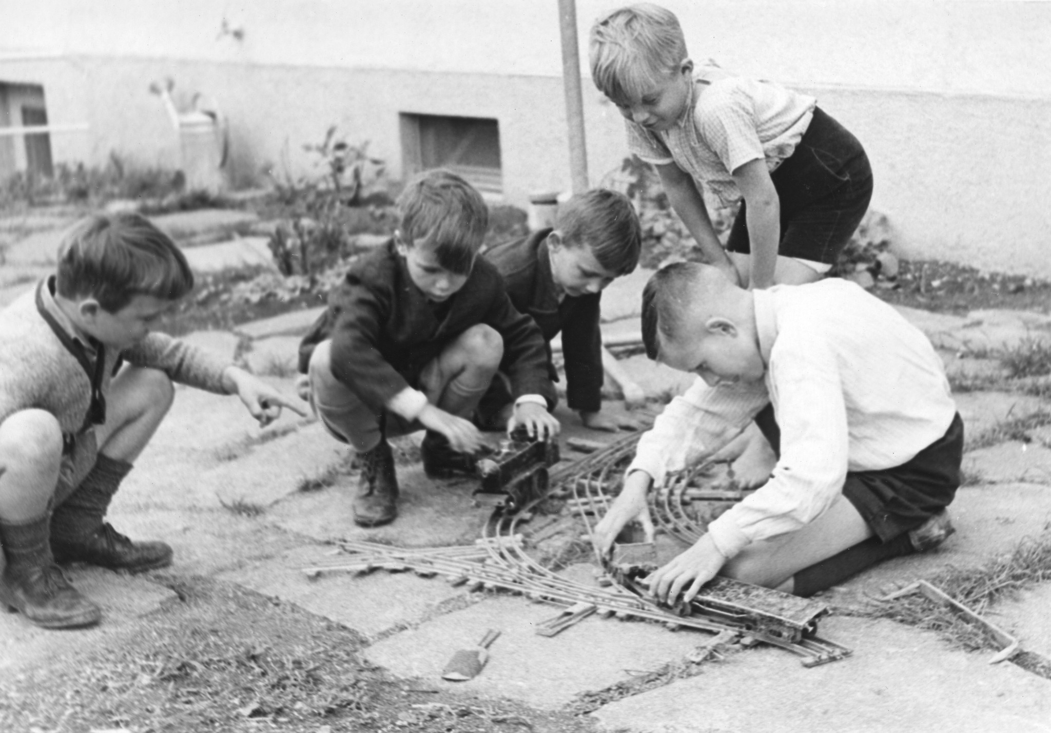 "Beim Spiel im Garten" (in der Schule?), Knaben spielen mit einer Modelleisenbahn, vermutlich in Zürich 1946