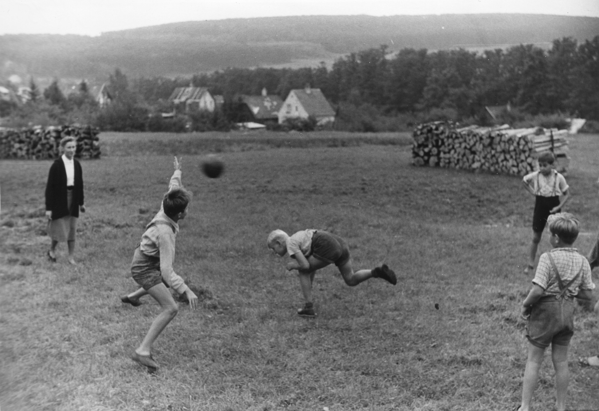 "Sommer 1953 - Hördlwald: Ferien für Flüchtlingskinder mit Hilfe des Schweizerischen Arbeiterhilfswerkes und der Schweizer Europahilfe. Volkshilfe Wien". Kinder spielen auf einer Wiese ein Ballspiel