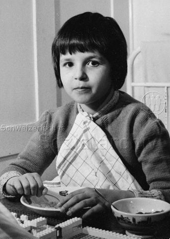 "Heimkinder" - Kind beim Essen am Tisch, auf dem Tisch liegen Lego-Steine; um 1960