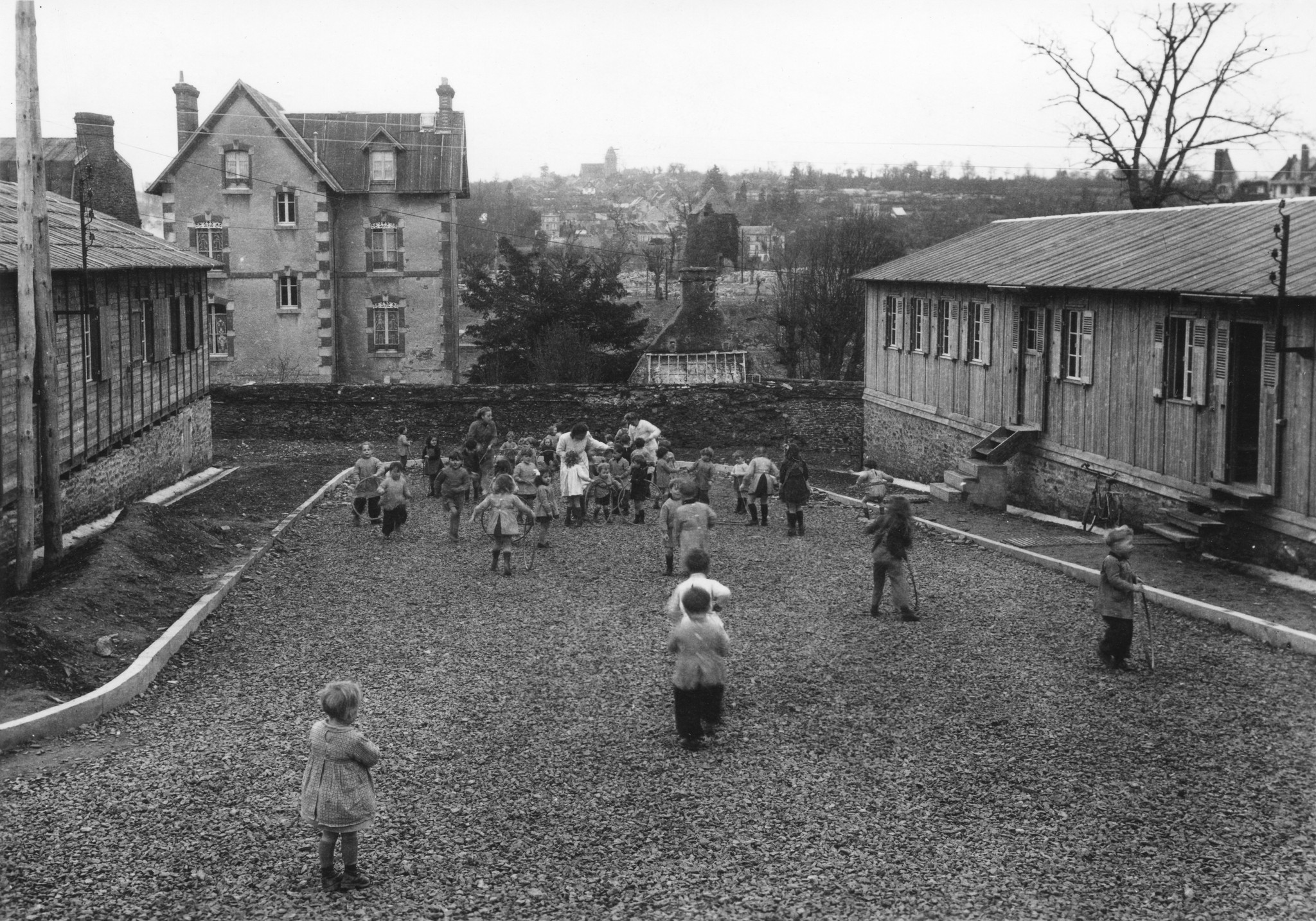 "Saint-Lô [1946], Enfants de la Garderie jouant entre le Foyer et l'Ouvroir", [Sozialzentrum des SAH, "Don Suisse", "Ouvert à toute la population de St-Lô"]