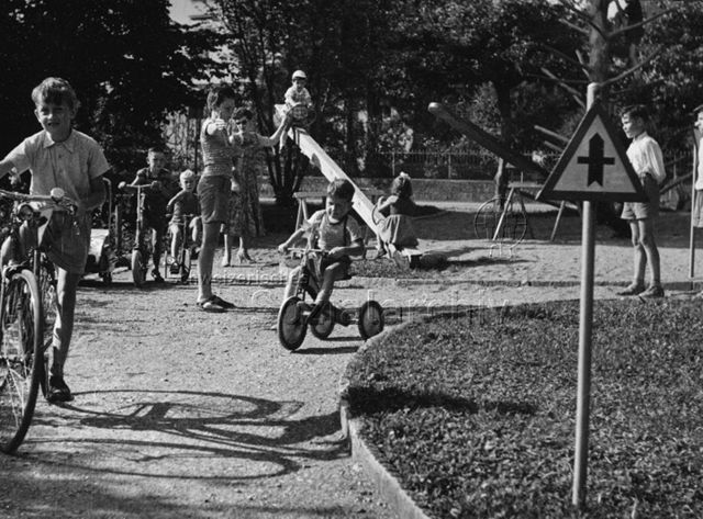 Kinder mit Fahrrädern, ein Junge spielt den Verkehrspolizisten, um 1965