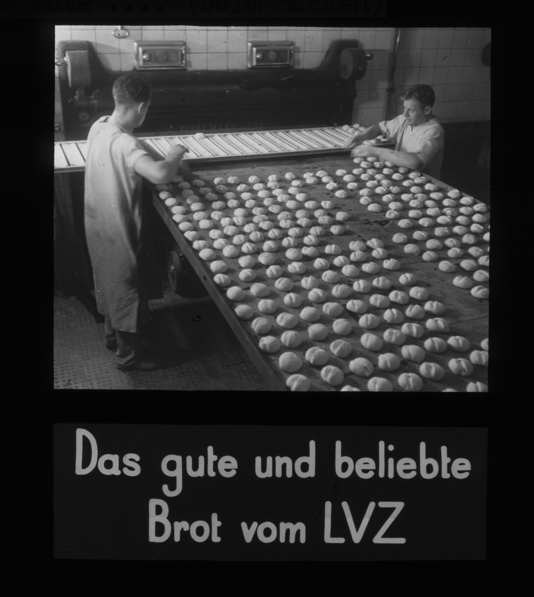 Dia: Zwei Bäcker beim Aufreihen von Brötchen auf Backblech, dazu Text: "Das gute und beliebte Brot vom LVZ".