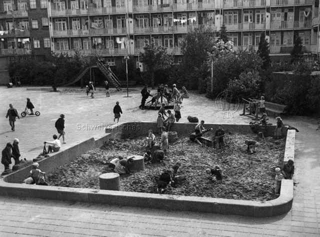 "Ein von Häusern eingeschlossener Spielplatz für Grossstadtkinder (Amsterdam)" - spielende Kinder, Sandspielplatz, Rutschbahn, Drehkarussell; um 1960
