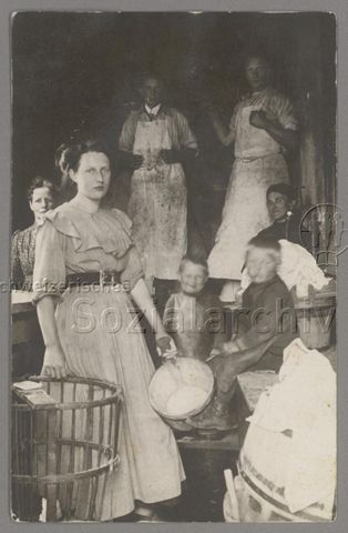 Wäscherinnen mit Holzbottichen, zwei Knaben und im Hintergrund zwei Männer mit schmutzigen Schürzen, um 1910