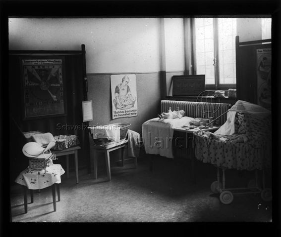 Diaserie zum Thema Säuglingspflege; Präsentation verschiedenster Utensilien zur Säuglingspflege; eine Waage, eine kleine Badewanne, ein Wickeltisch, Hygieneartikel und ein Kinderbett; Plakat mit Aufschrift "Tägliches Bad ist für die Gesundheit nötig"; um 1930