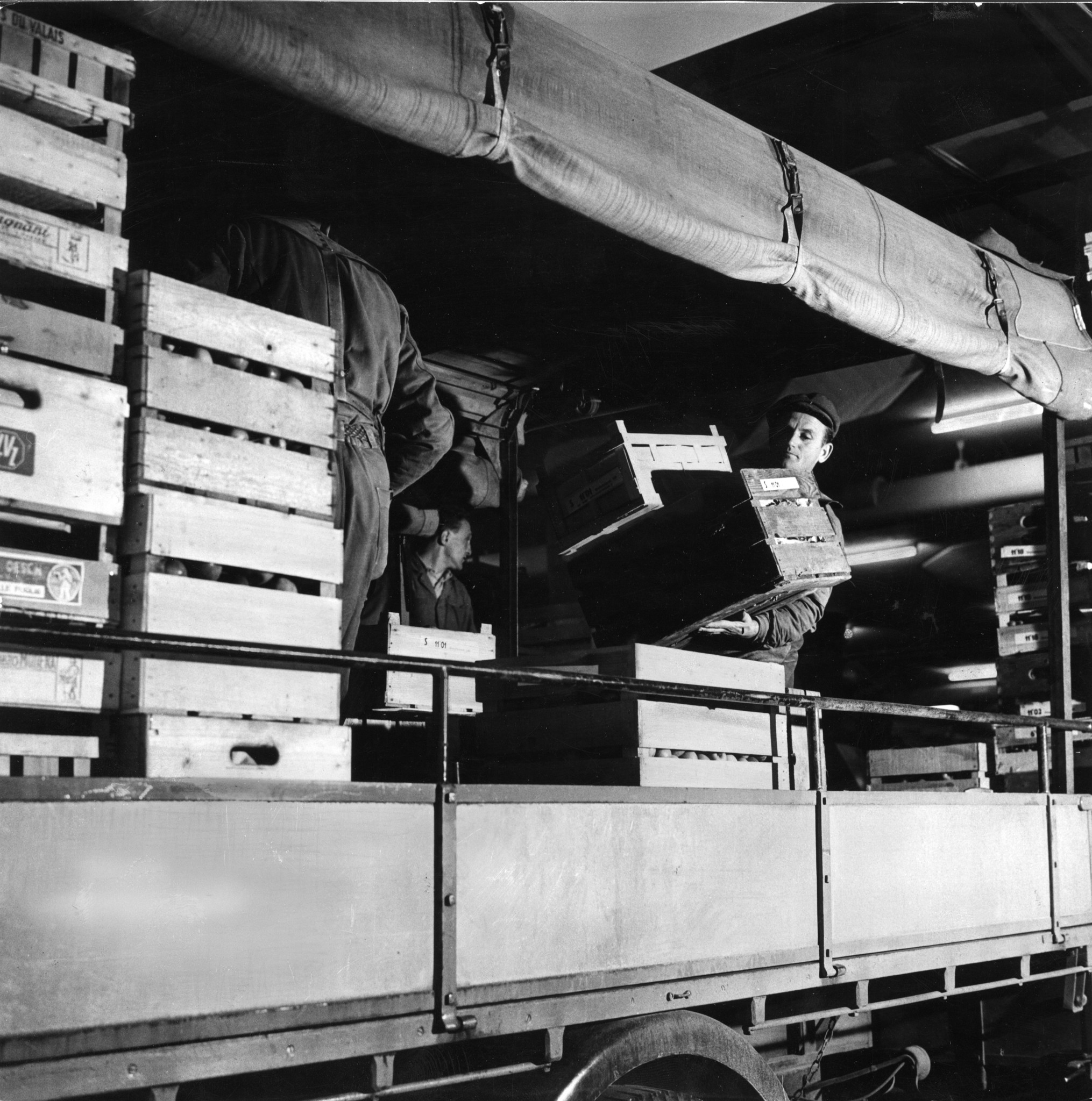 Männer beim Beladen oder Entladen von Gemüse / Früchten auf einem Lastwagen