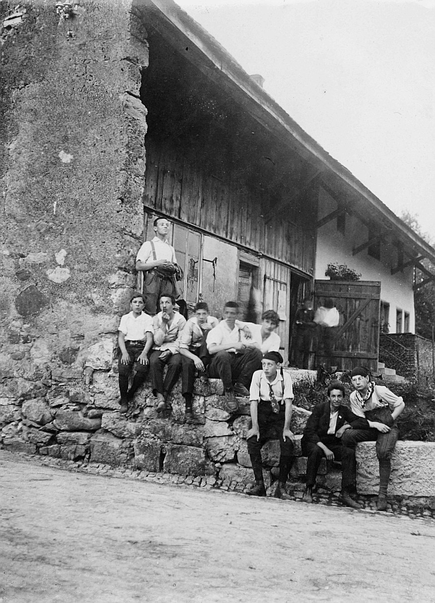Gruppenporträt der Wandervögel-Ortsgruppe Zürich-Altstadt, die bei einem Bauernhof (vermutlich) sitzen (1912)