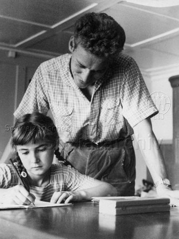 PraktikantInnenhilfe - Mädchen bei den Hausaufgaben, Praktikant steht helfend zur Seite; um 1965
