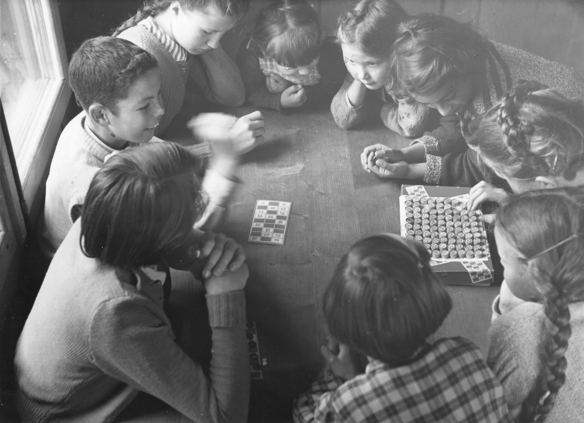 Kinder sitzen im Kreis an einem Tisch und spielen ein Spiel