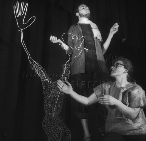 "Laienspiel, Volkstheater: Cabaret" - Ein Mann und eine Frau auf der Bühne, sie wendet sich zu einer Skulptur aus Draht hin; um 1970