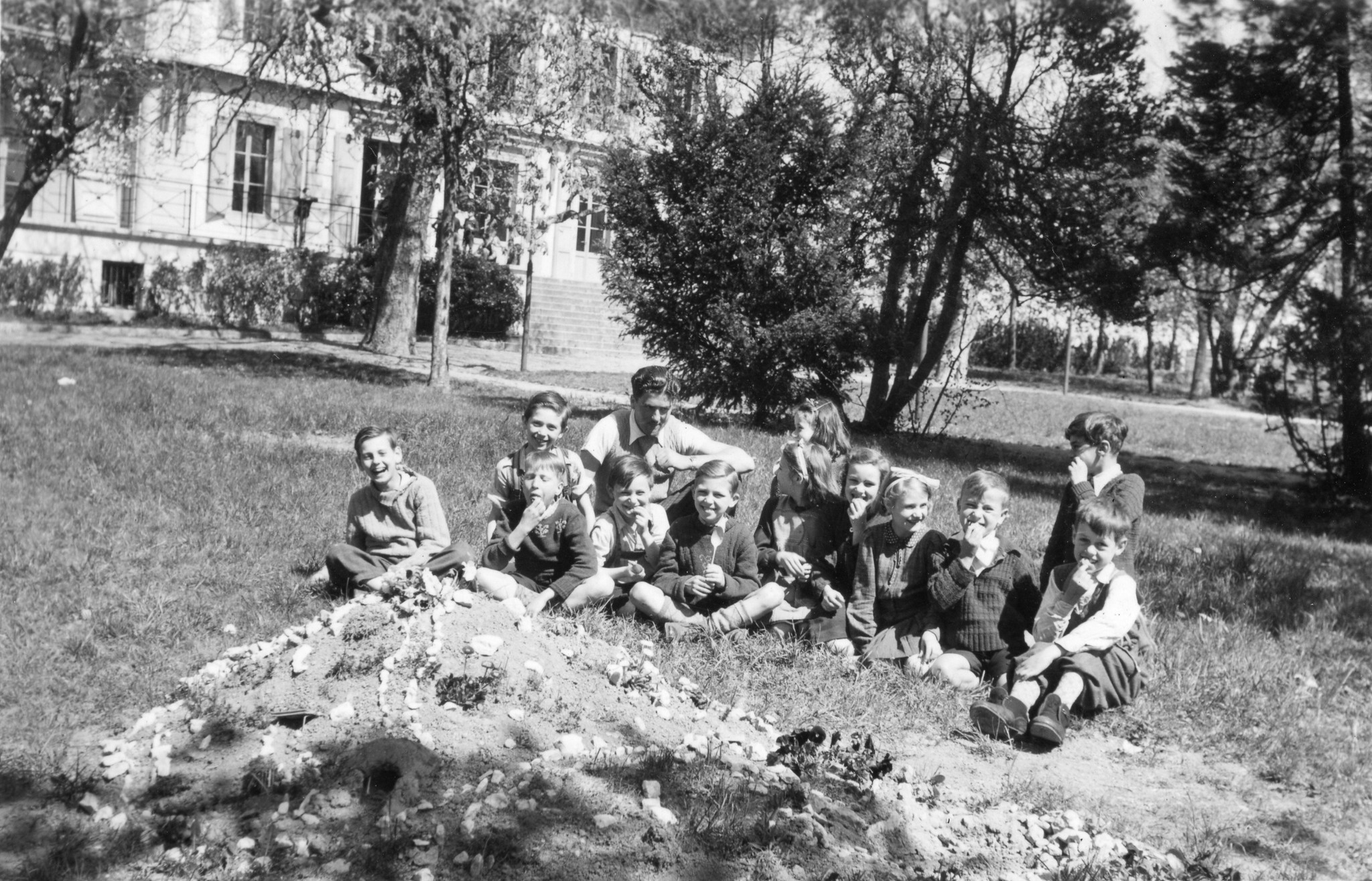 "Genève - Vieux Bois, Frühjahr 1946. Die Wienerkinder aus dem Heim."; Kinder sitzen auf der Wiese und essen