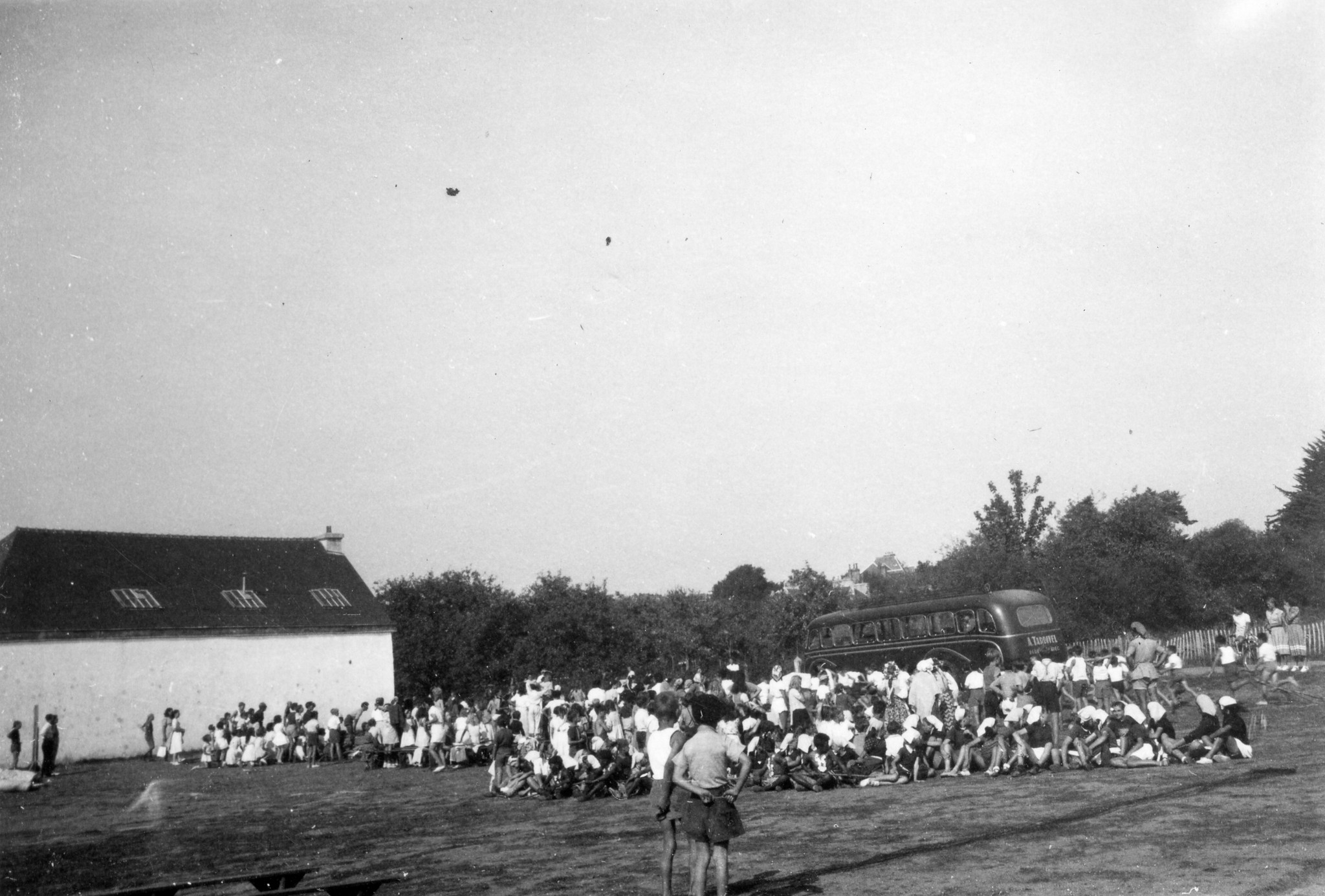 "Terrain de sports de St. Quay - Fête laique"; Sportplatz von St. Quay: Jugendliche warten sitzend auf einer Wiese