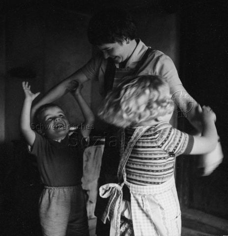Praktikantinnenhilfe - Praktikantin spielt mit zwei Kindern; um 1965