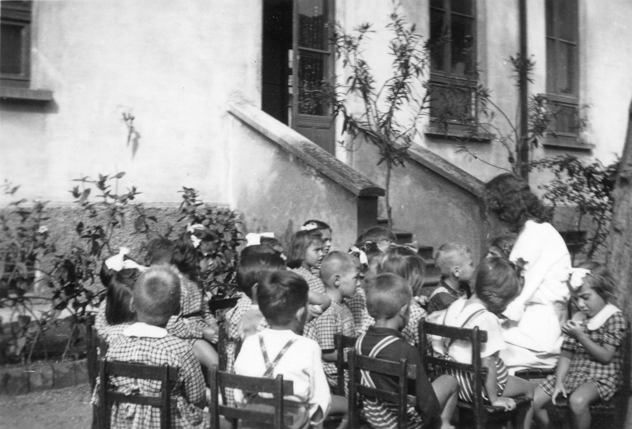 "Milano 1947. Asilo Italo-svizzero"; Kinder sitzen mit einer Betreuerin vor dem Haus