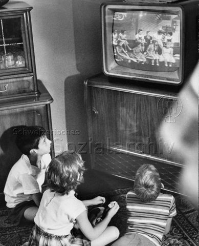 Kinder sitzen auf dem Boden und sehen fern; um 1960