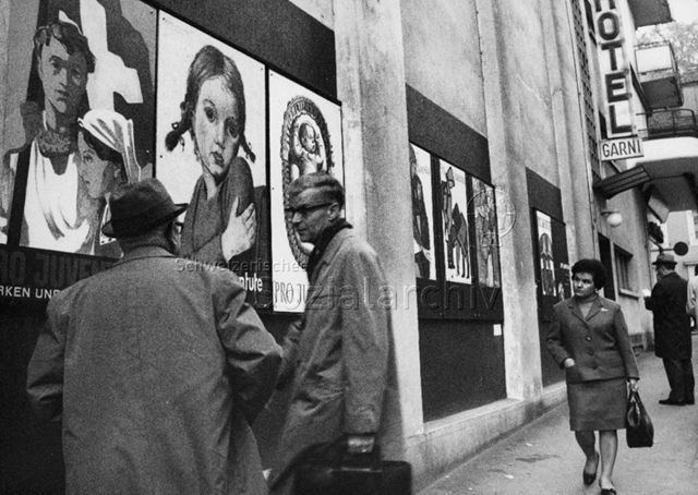 "Dr. Ledermann, Zentralsekretär, im Gespräch mit Hrn. Hagmann" - An der Wand des Hotel Garni sind Pro Juventute Plakate angebracht"; um 1965