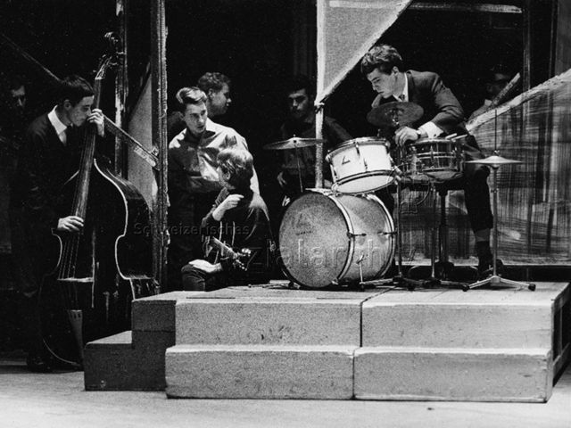 Band macht sich bereit für einen Auftritt, Schlagzeug, Kontrabass, Gitarre; um 1970