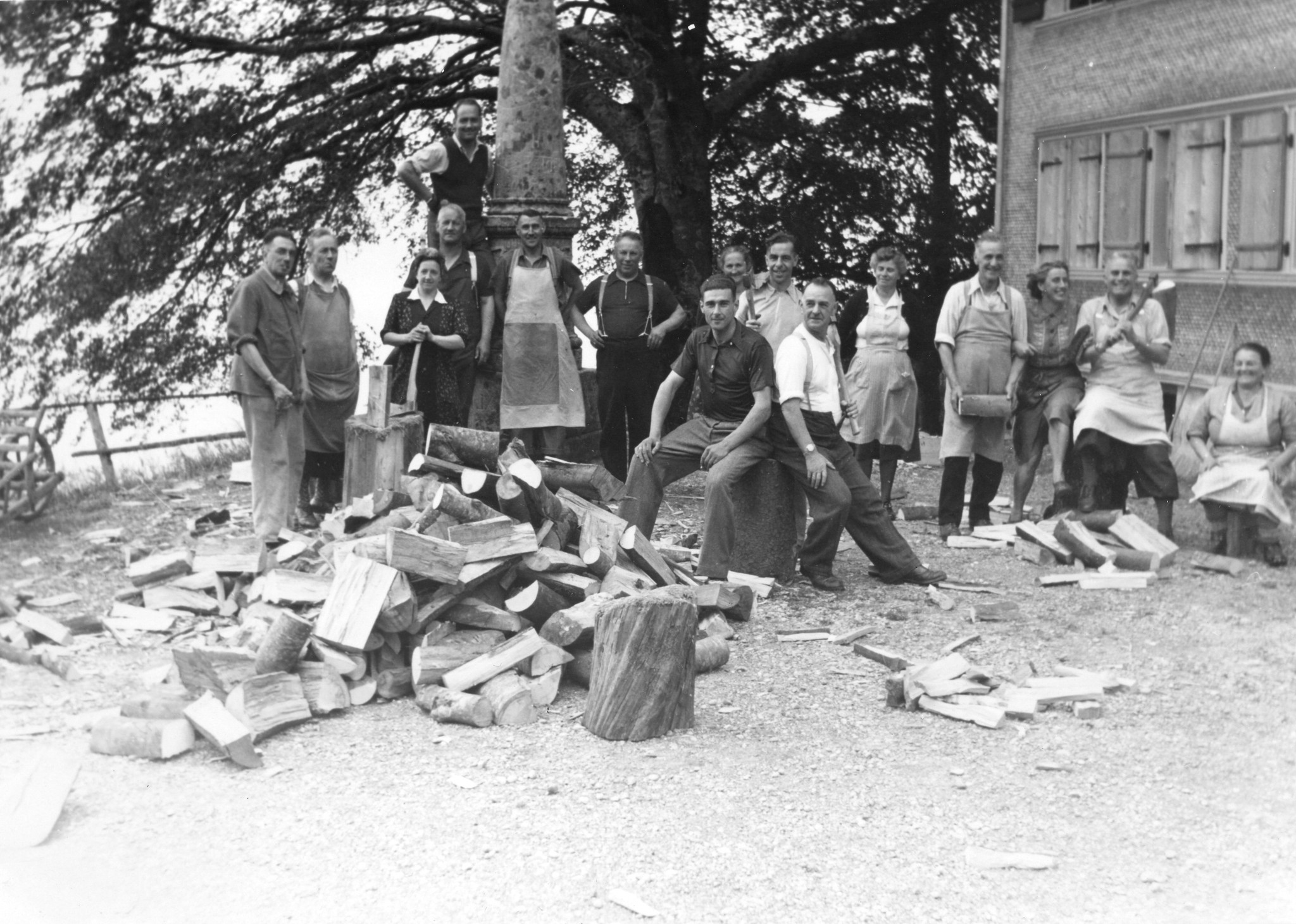 "Der Strassenbahner Männerchor bereitet das Holz für das kommende Lager vor", Männer und vier Frauen mit Holzklotzen und Haxen, in Österreich (?) um 1950 (Nachkriegszeit)