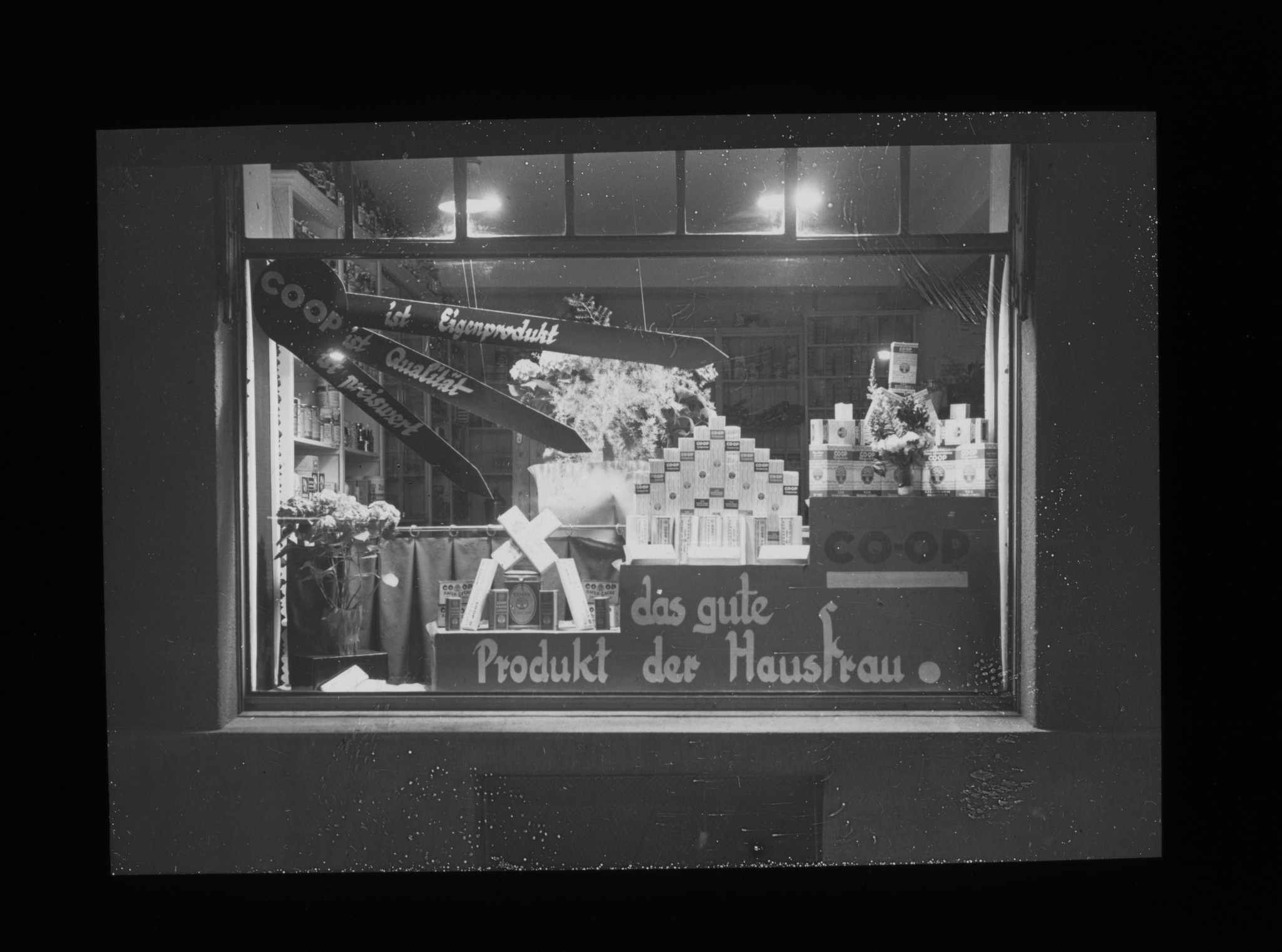 Dia: COOP/LVZ-Filiale, im Schaufenster Produkte und Text: "COOP ist Eigenprodukt, ist Qualität, ist preiswert, das gute Produkt der Hausfrau."