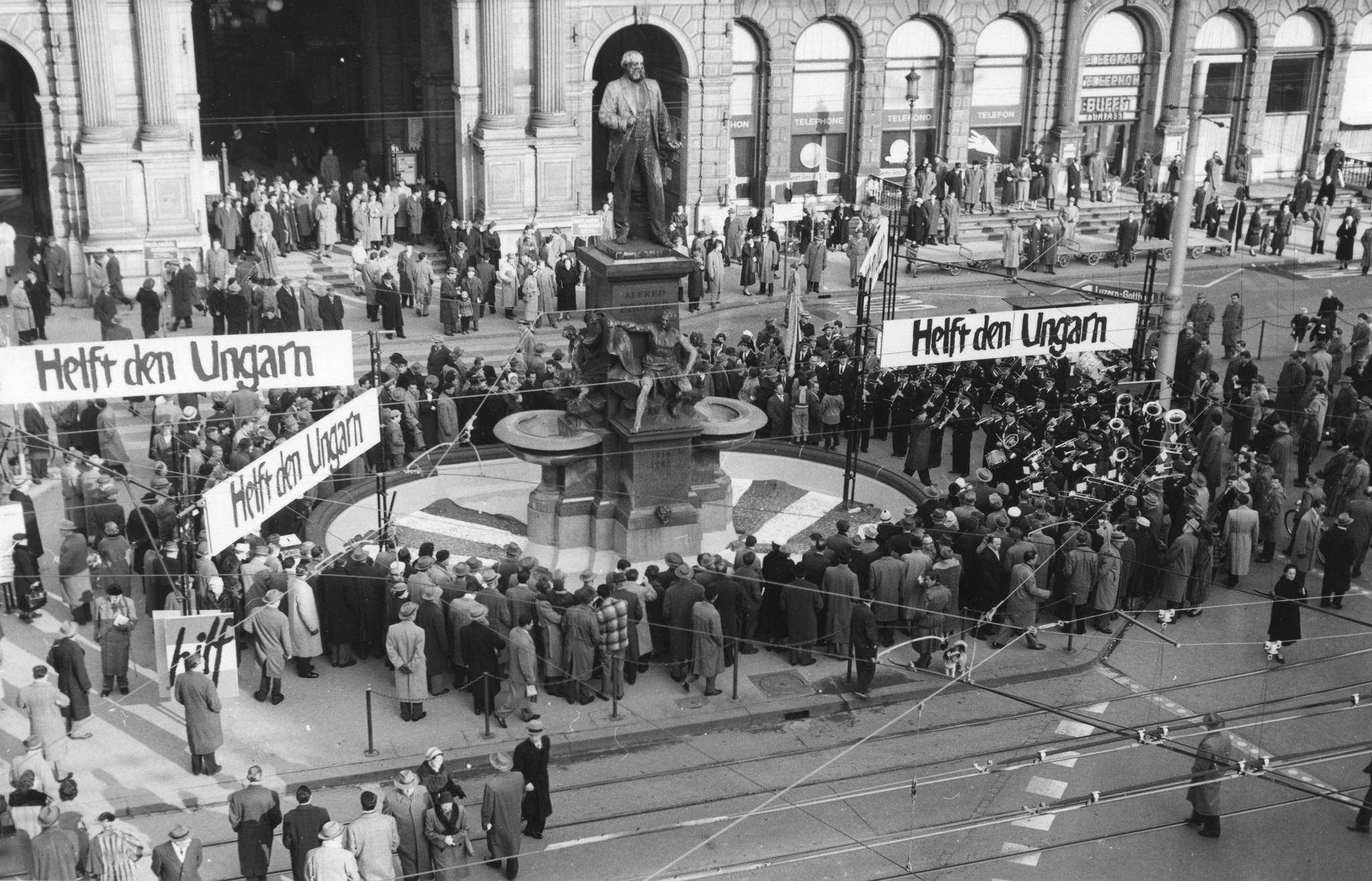 Menschen demonstrieren auf dem Bahnhofplatz in Zürich mit Plakaten mit der Aufschrift "Helft den Ungarn"