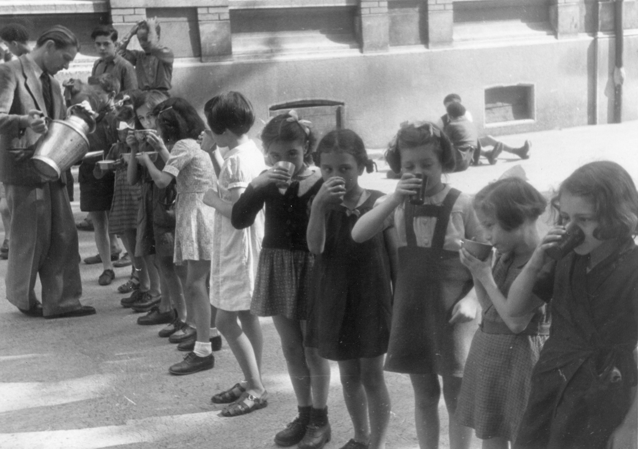 "Saint-Etienne, 1945. Der Lehrer verteilt seinen deficienten Schülern in der Znünipause eine Tasse "Don Suisse"-Milch. Die gut und sorgfältig zubereitete Milch schmeckt ausgezeichnet, die Mädchen möchten lieber zwei Tassen anstatt nur einer."