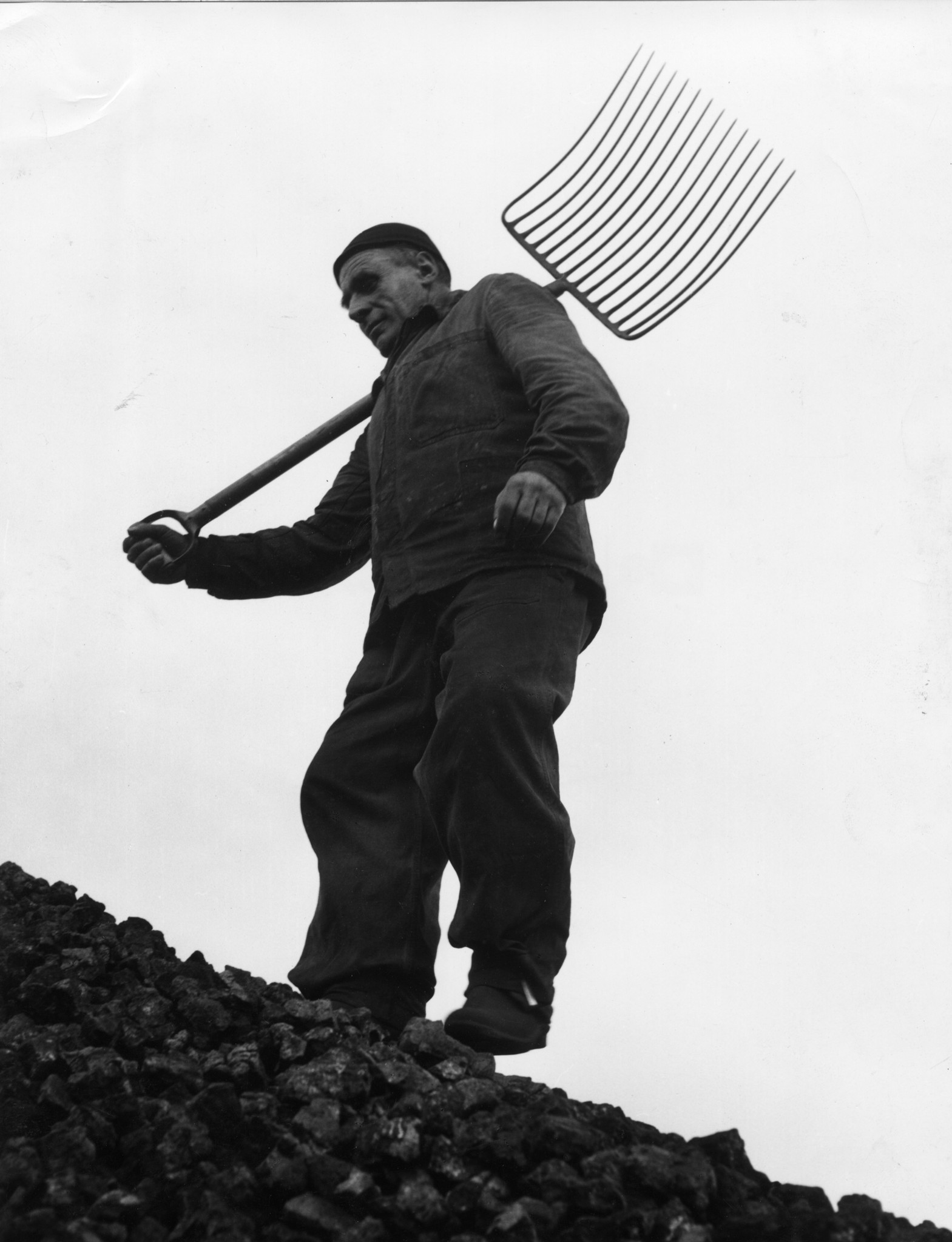 Arbeiter mit Schaufel auf einem Haufen von Brennmaterial
