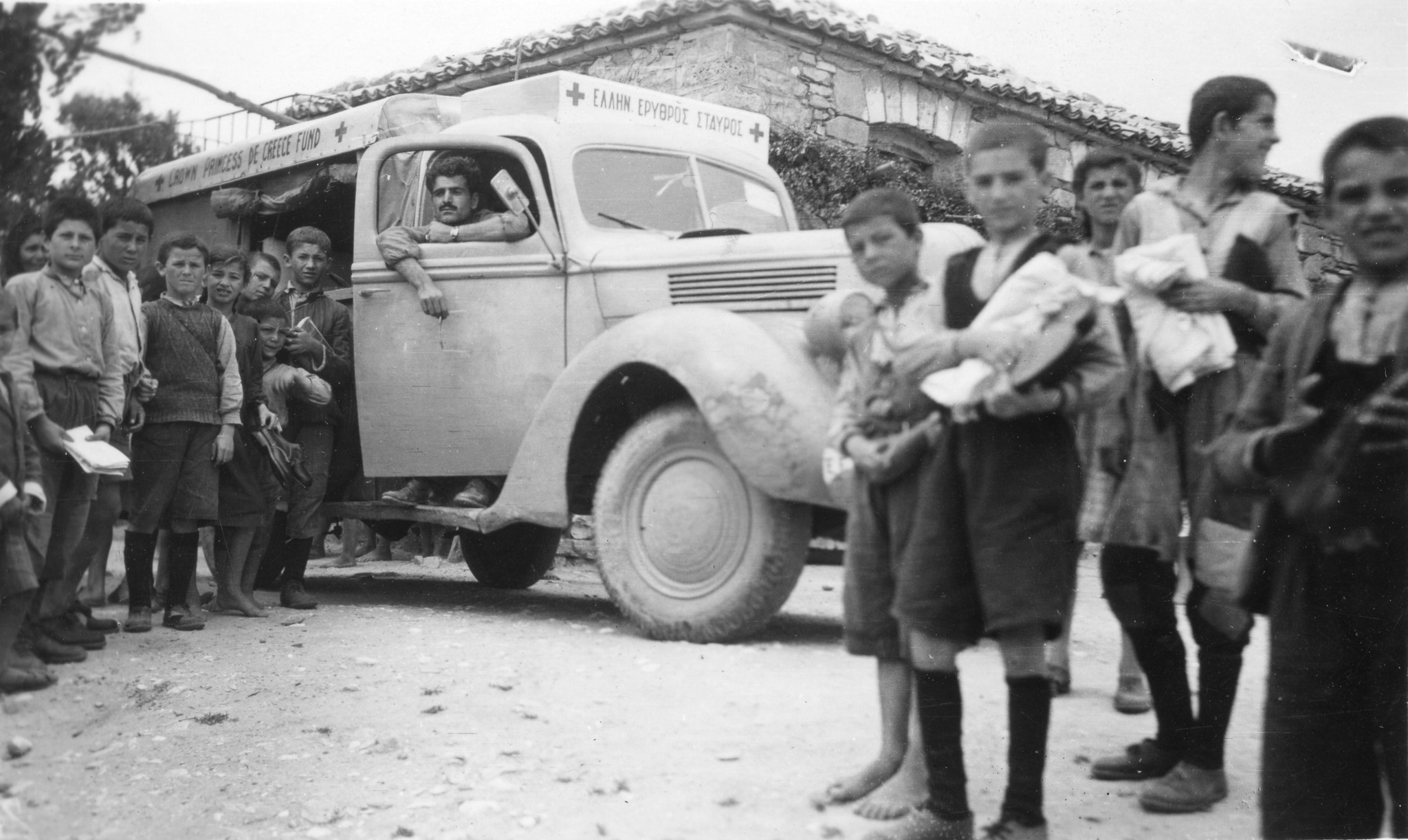 Kinder posieren vor einem Hilfsgüterwagen der "Crown Princess de Greece Fund" mit Chauffeur