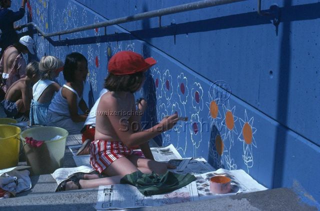 "Spielaktion Lausen" - Kinder bemalen eine Wand mit Blumen und Sonnen; um 1975