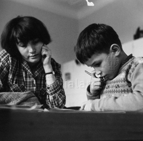 Frau unterstützt Jungen beim Lernen; um 1970
