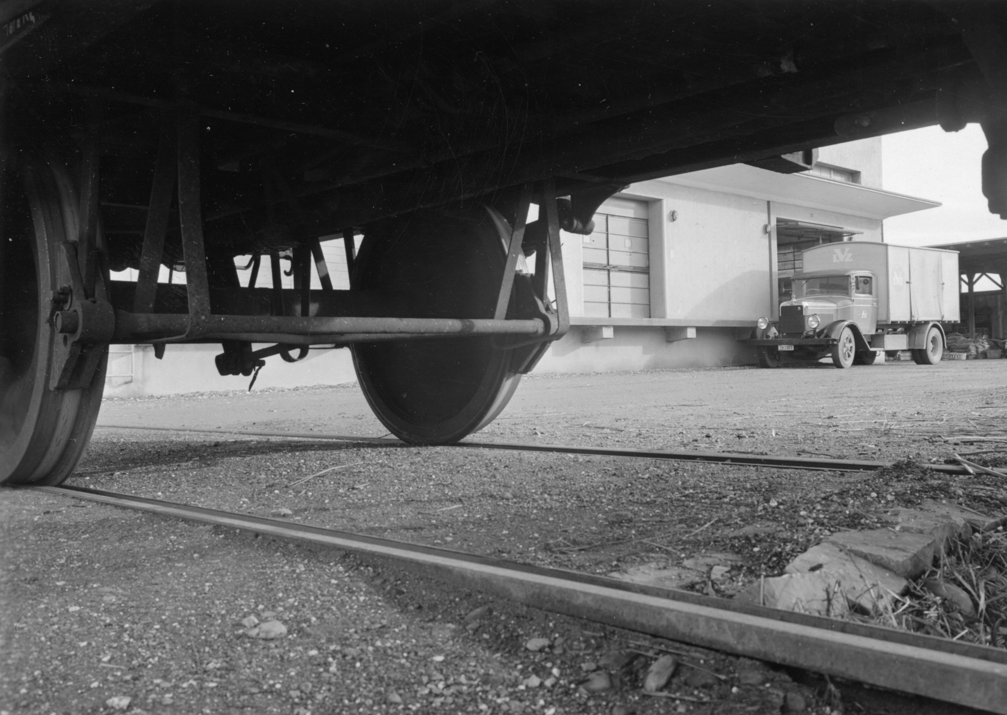 Eisenbahnwaggon und Lastwagen des Lebensmittelvereins Zürich beim Holzlager an der Turbinenstrasse, Aufnahme der Unterseite mit Rädern und Geleise