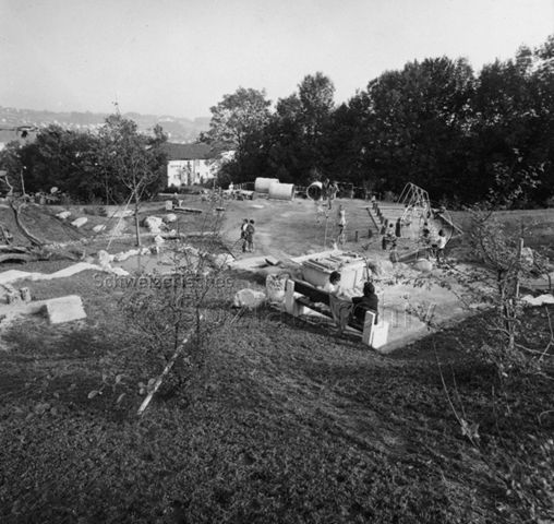 "Siedlungsspielplatz Adliswil" - Ansicht der Anlage mit Betonröhre, Schaukel, Klettergerüst und Wippe; 1971