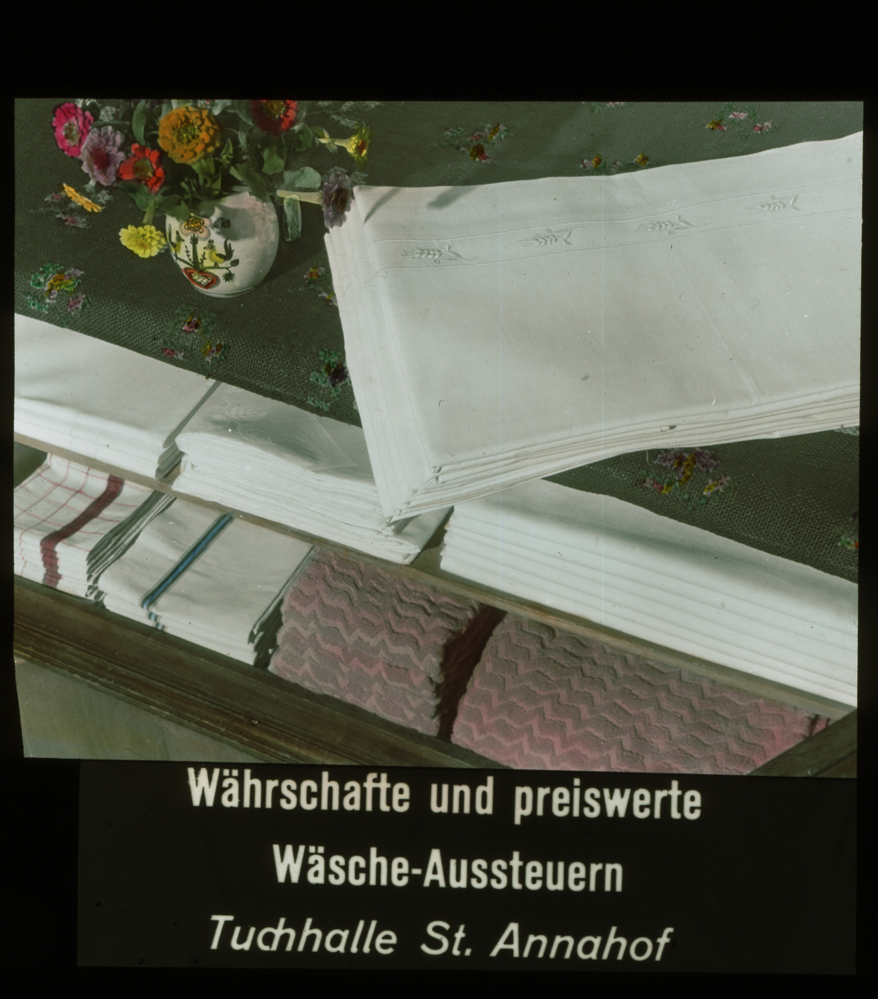 Dia: Wäsche und Blumenstrauss, dazu Text: "Währschafte und preiswerte Wäsche-Aussteuern Tuchhalle St. Annahof".
