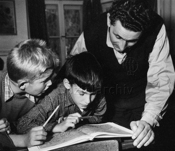 Mann und zwei Jungen beim Studieren einer Karte im Atlas; um 1965