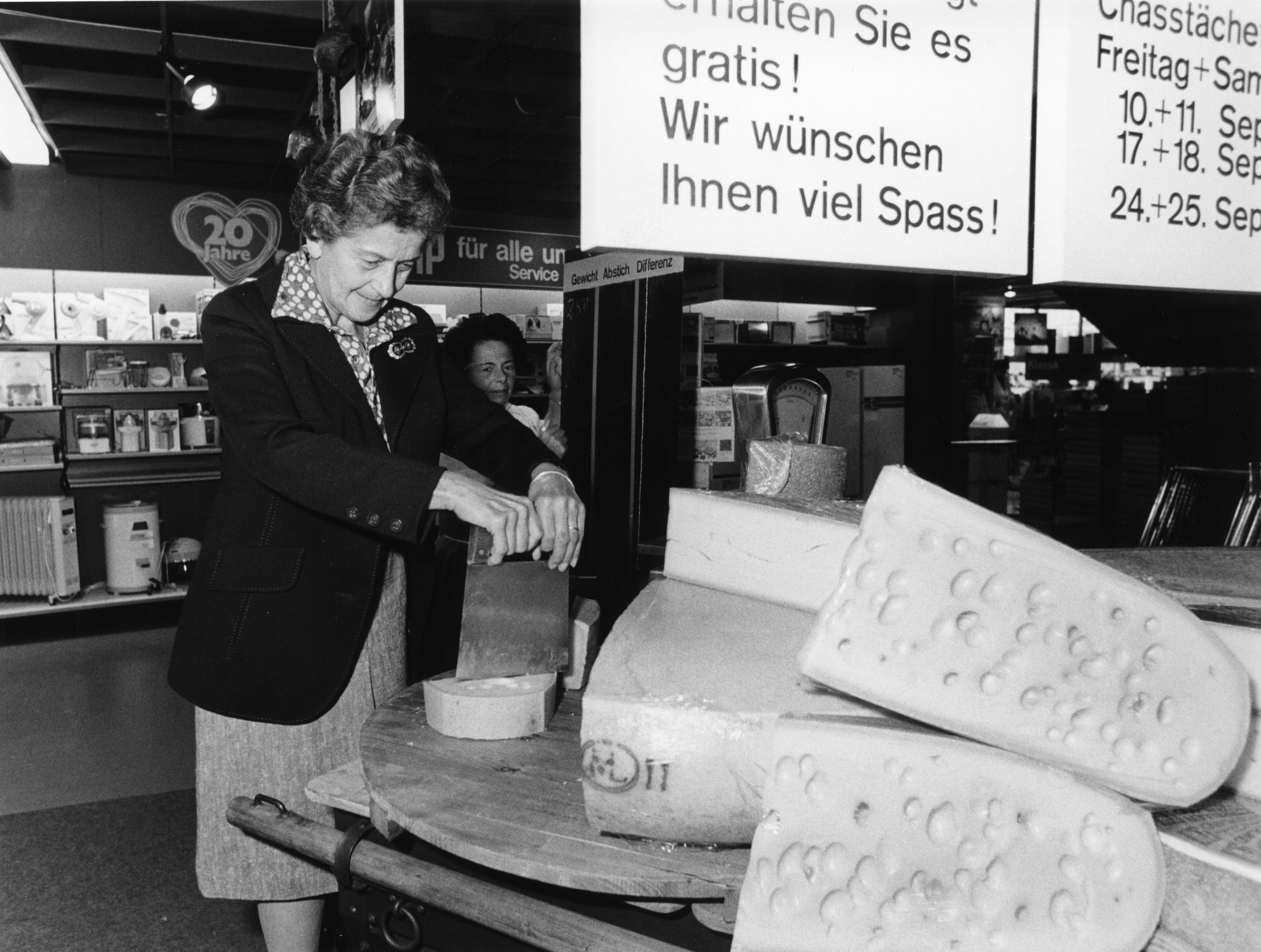 Werbeaktion in einem Laden des Lebensmittelvereins Zürich: Käse-Abstechen und Schätzen des Gewichts, Angestellte und Kundin