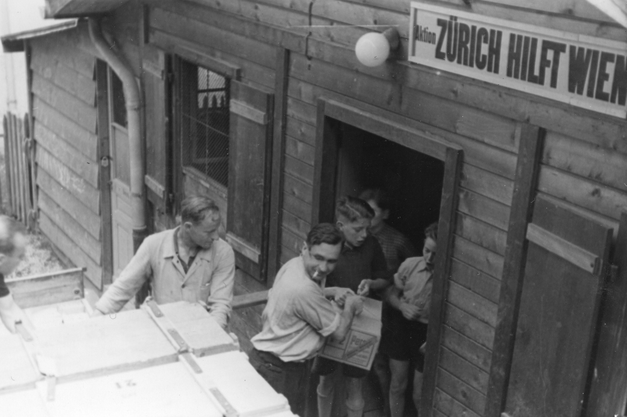 "Zürich, Mai 1946. Die Schaffhauser-Sammlung wird ausgeladen. Schulkinder helfen bei der Arbeit."; Knaben tragen Kisten in die Baracke "Zürich hilft Wien"