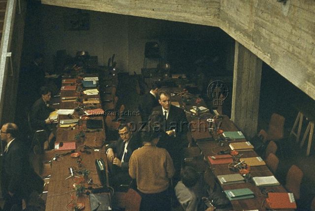 "Freizeitanlagen, Gemeinschaftszentren: FZA Heuried, Zürich, grosser Saal" - Lange Tische mit Sitzungsmappen und Mikrofonen, Frauen und Männer in Anzügen; SAJV Konferenz 1966