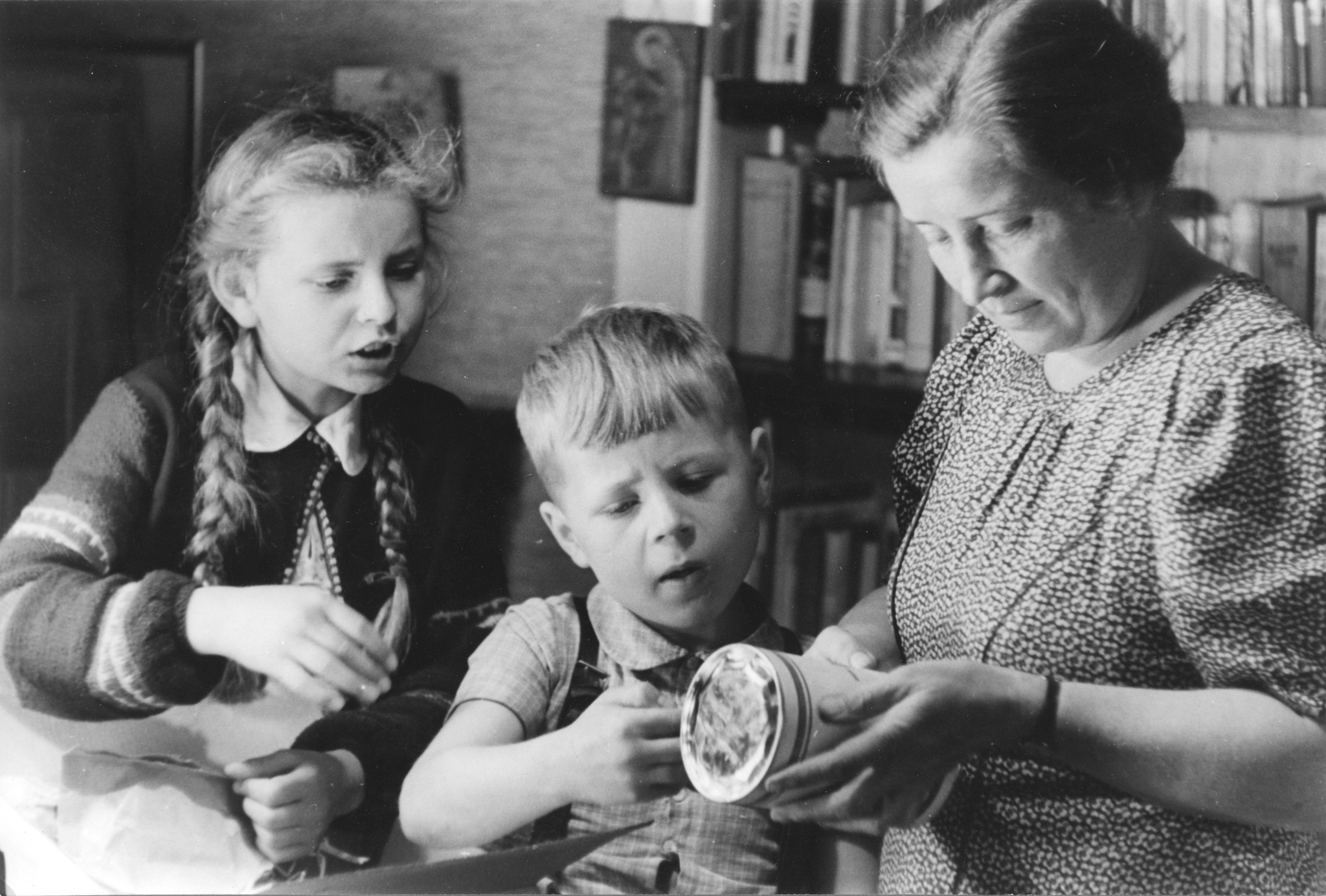 "Hamburg, Sommer 1948: ein Freipaket kommt an!"; Zwei Kinder und ihre Mutter betrachten eine Büchse
