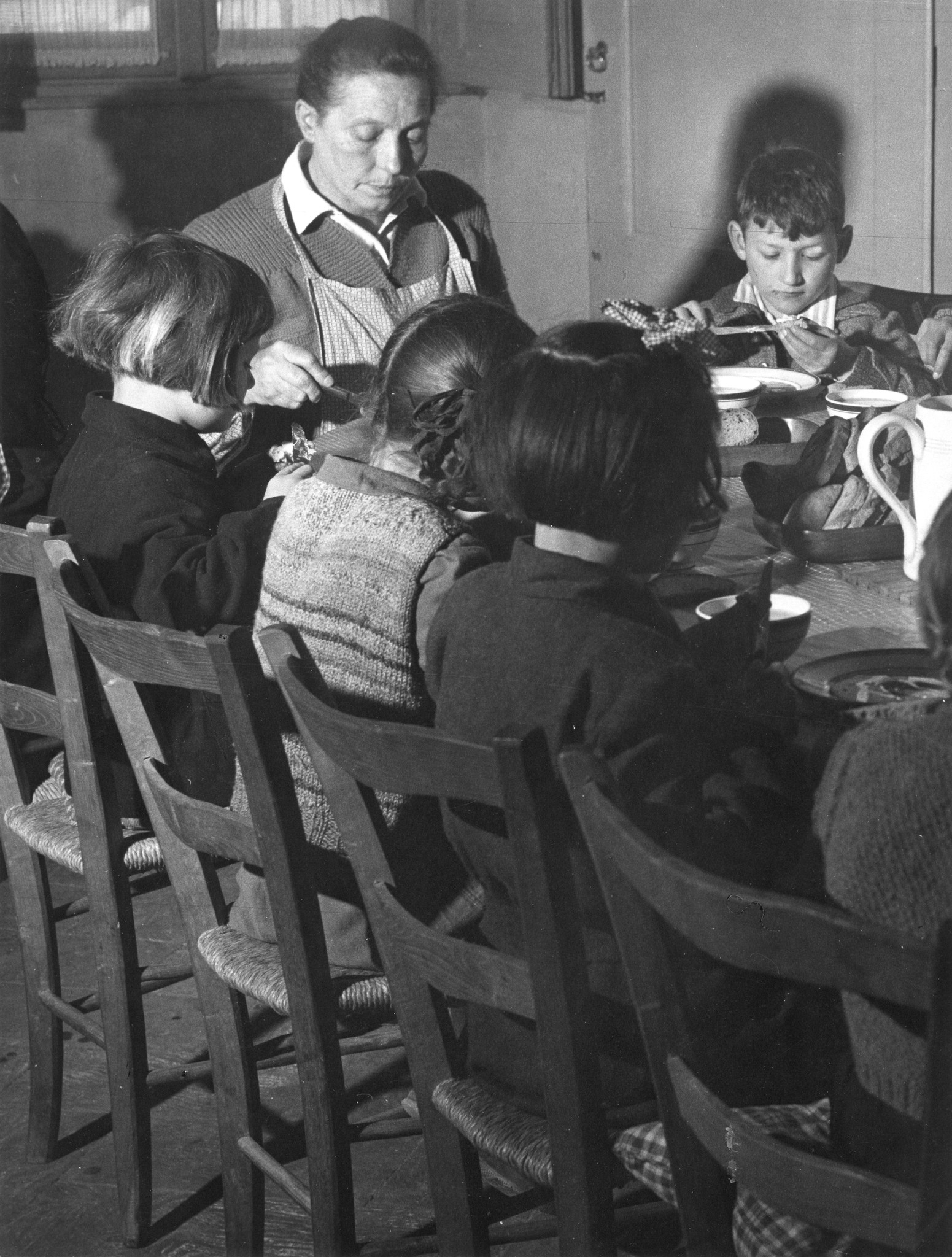 Kinder essen zusammen mit einer Betreuerin ihr Abendessen