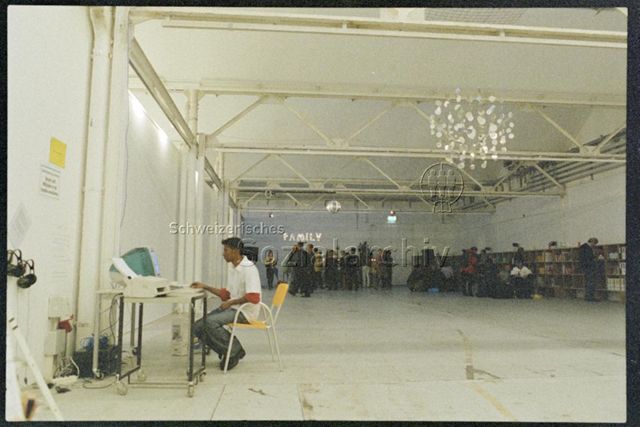Shedhalle mit Bar, im Vordergrund Person am Computer
