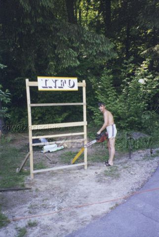 Bosco della Bella, Feriendorf für kinderreiche Familien - Mann mit Motorsäge vor Holzkonstruktion mit "Info" Beschriftung; 2000
